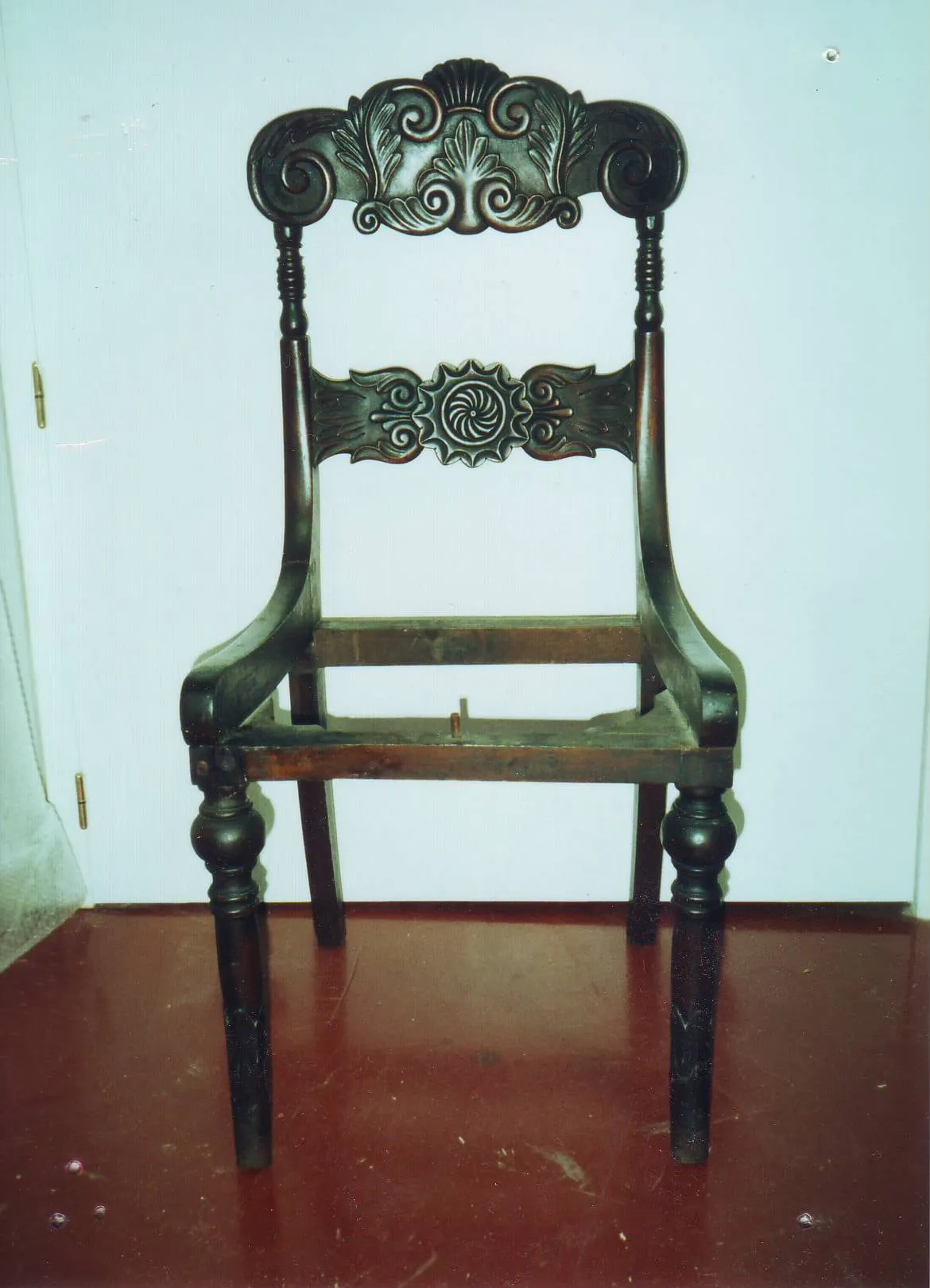 Silla de madera tallada, sin asiento, durante la restauración