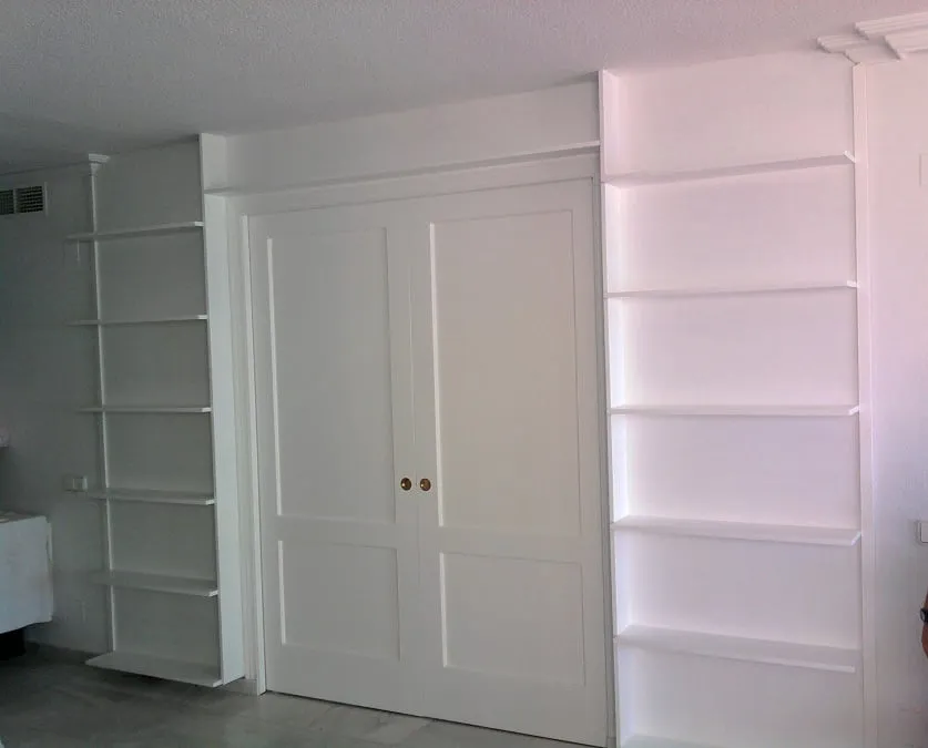 Librería blanca con puertas correderas en el centro y baldas a los lados