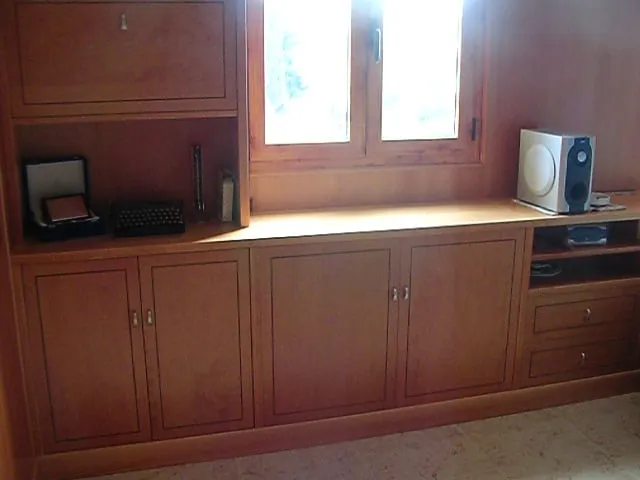 Mueble de madera integrado bajo una ventana, con puertas y hueco para equipo de música