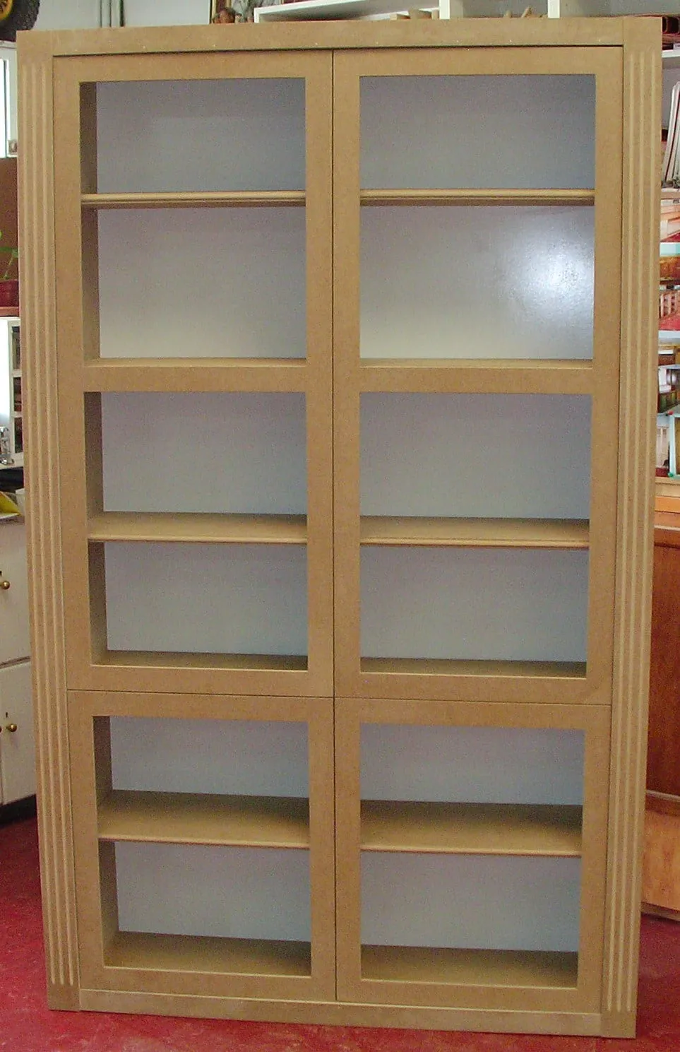 Librería alta de madera con puertas de cristal, en el taller